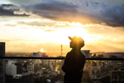 Woman standing in city against sky during sunset