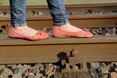 Low section of woman wearing shoes walking on railroad track