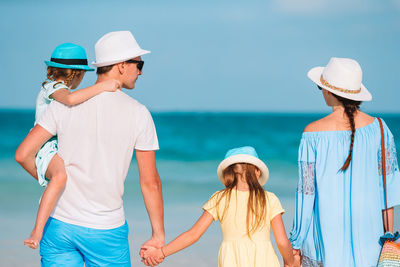Rear view of friends standing at beach