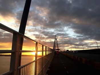 Road by sea against sky during sunset