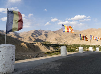 Buddhist flags waving road against sky