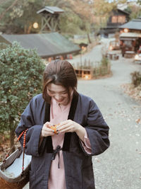 Girl wears japanese traditional clothing  with basket  on arm  is pealing an orange while walking 