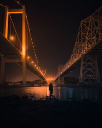 Silhouette person against suspension bridge at night