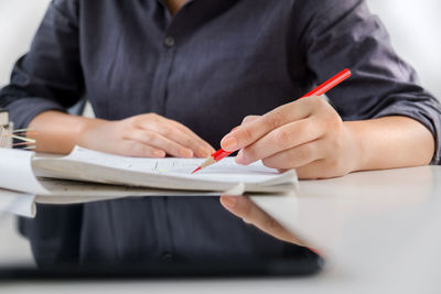 Midsection of woman holding umbrella on table