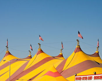 Low angle view of flags against clear blue sky