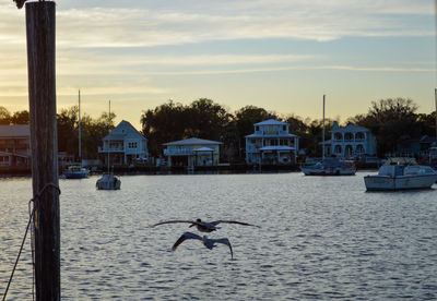 View of sea by buildings against sky during sunset