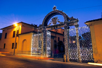 Illuminated building by street against sky at night