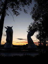 Silhouette statue against sky at sunset