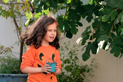 Portrait of young woman standing against plants