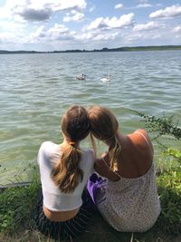 Rear view of women sitting by sea