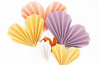Purple, yellow, and orange colored paper hearts on white background