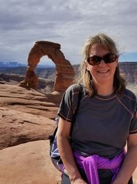 Young woman wearing sunglasses on rock against sky