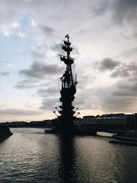 Silhouette of bridge over river against cloudy sky