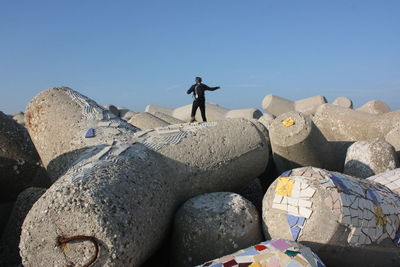 Rear view of man standing on rock against clear sky