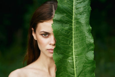 Close-up portrait of young woman with leaves outdoors