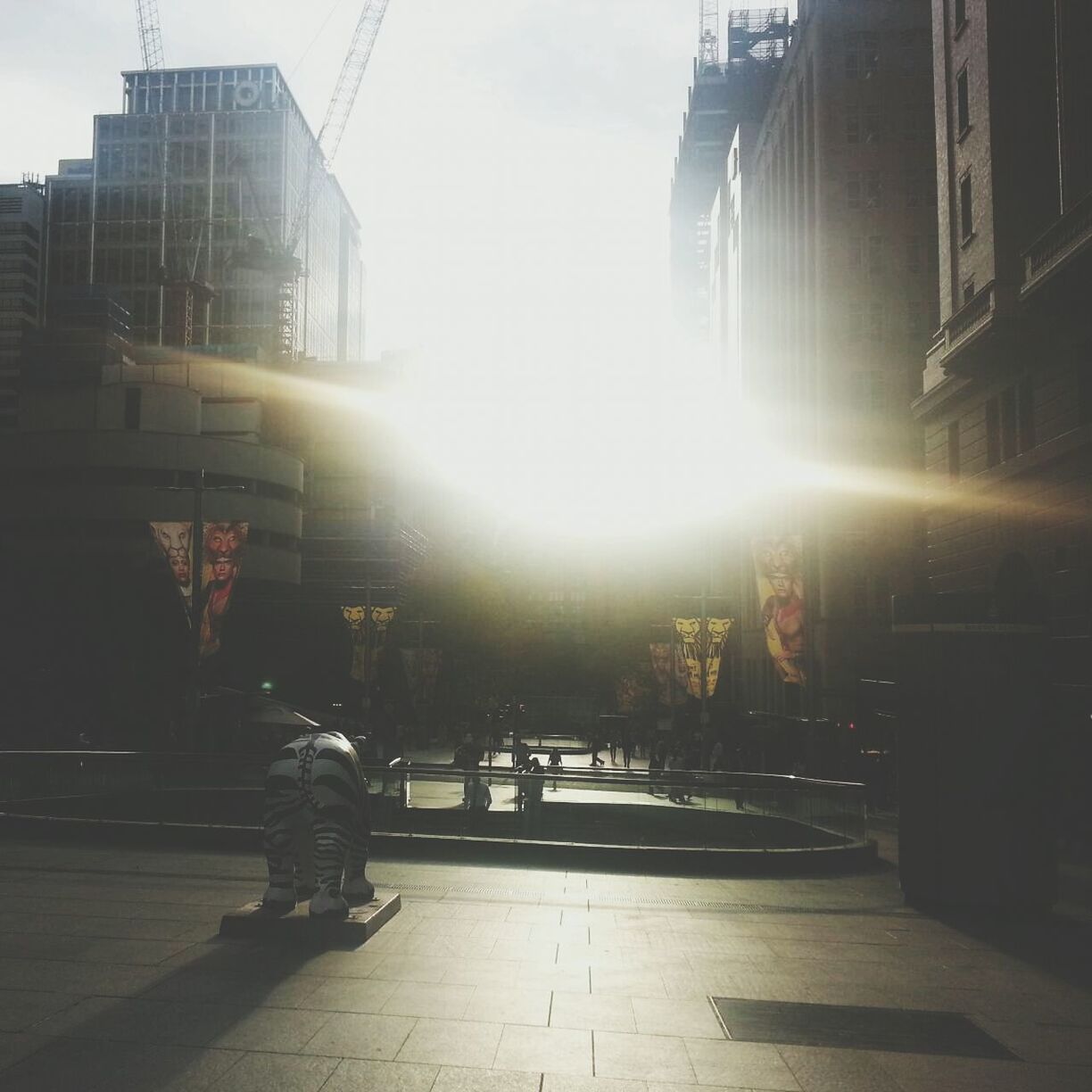 architecture, building exterior, built structure, city, sunlight, the way forward, sunbeam, building, city life, sun, men, street, lifestyles, walking, modern, office building, lens flare, person, skyscraper