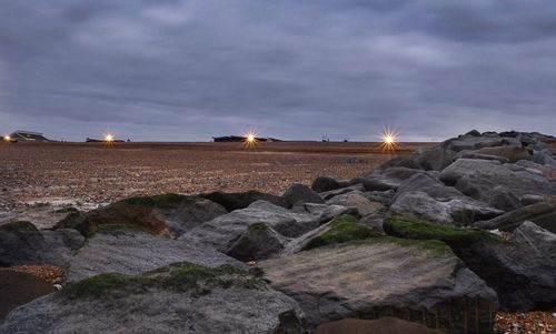 Rocks on shore against sky during sunset