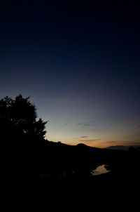 Silhouette trees on landscape against sky at sunset