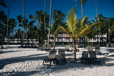 Empty chairs and tables at beach against sky