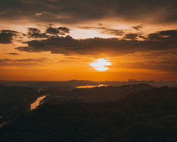 Amazing aerial view on the orange sky, sunset sun and clouds far from the city.