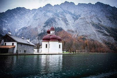 Built structure by lake and mountains against sky