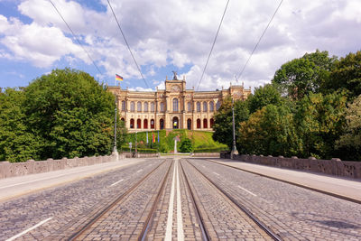 Railroad tracks in city against cloudy sky
