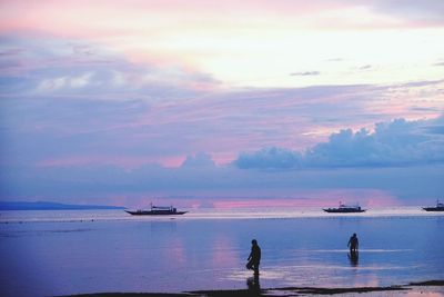 Silhouette people on beach against sky during sunset