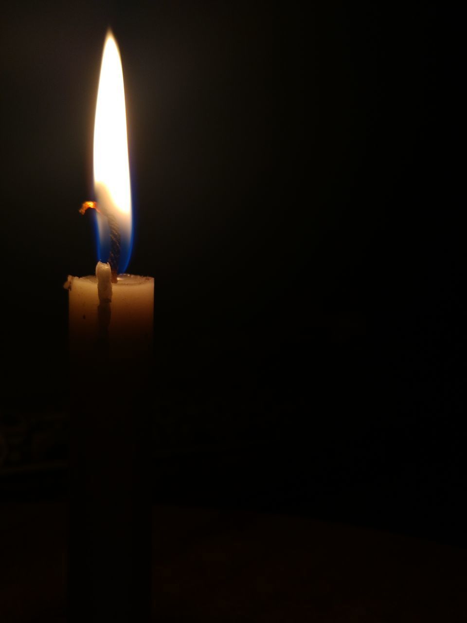 CLOSE-UP OF LIT CANDLE IN DARK