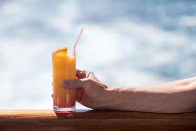 Cropped hand of man having drink on boat in sea