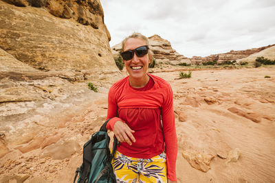 Desert hiker with slanted sunglasses and messup up shirt laughing