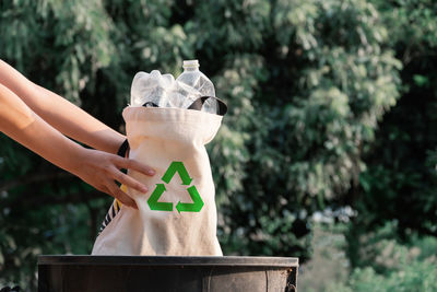 Midsection of woman holding plant against trees