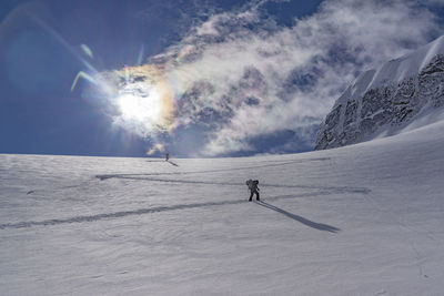 People skiing on snow field against sky