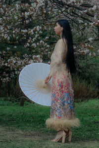 Young woman with umbrella standing on field