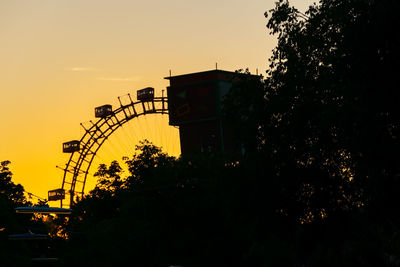 Low angle view of silhouette ferris wheel against sky at sunset