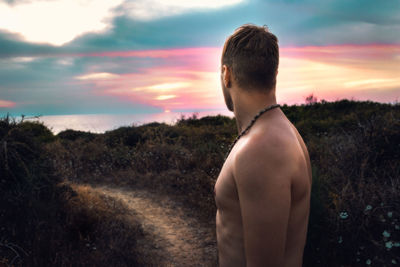 Rear view of shirtless man looking at sunset