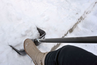 Low section of person holding snow in shovel during winter
