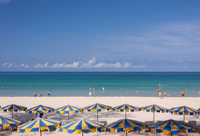 People on beach against blue sky