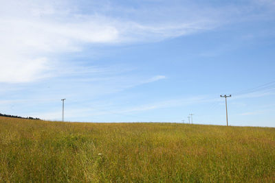 Electricity pylon on field against sky