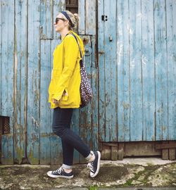 Full length of woman standing against yellow wall