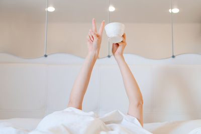 Young woman with a coffee mug in bed with white linens. minimal happy morning
