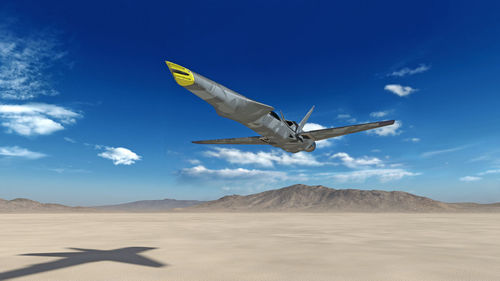 Airplane flying over desert against blue sky