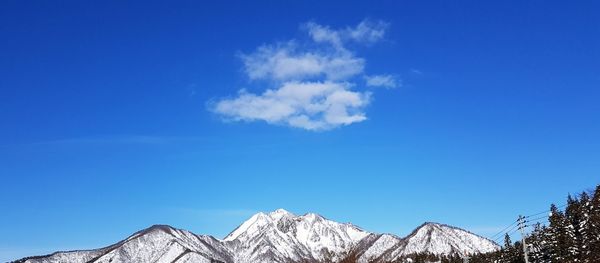 Low angle view of snowcapped mountains against blue sky
