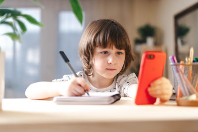 Back to school. distance learning online education. kid boy studying at home with mobile cell phone. 