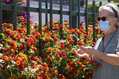 Senior woman touching flowers in park