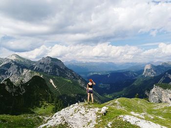 Rear view of woman standing on mountain against sky