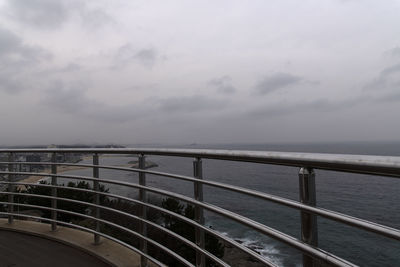 Scenic view of guard rail with sea against sky
