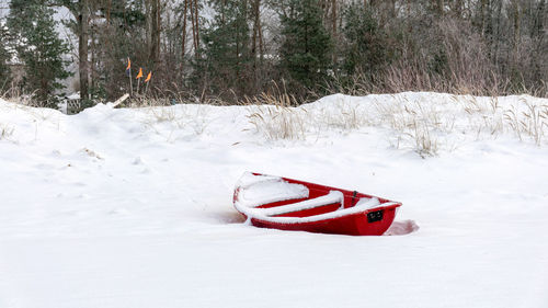 Winter landscape from the seashore, red fisherman's boat on the seashore, sand and ice texture 