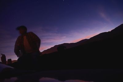 Silhouette man standing on mountain against sky at night