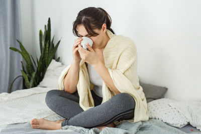 Young woman sitting on bed at home