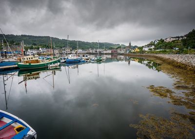 Boats in river against cloudy sky